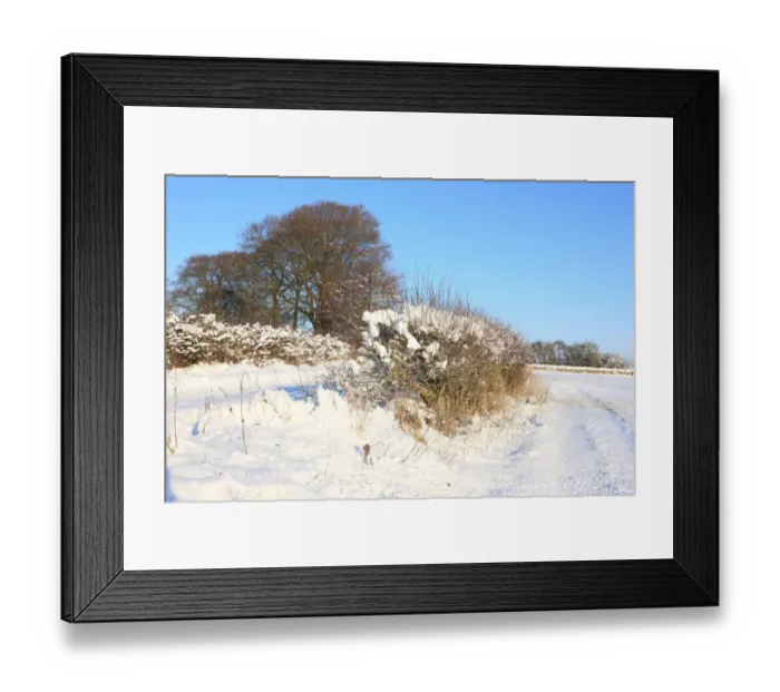 Framed Print : Burford. A road and a hedge covered in snow on cold winters day near the Framed Print : Burford. A road and a hedge covered in snow on cold winters day near the