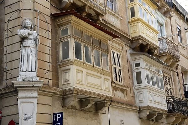 Statue of St. Francis and covered wooden balconies in the street in Valletta, Malta