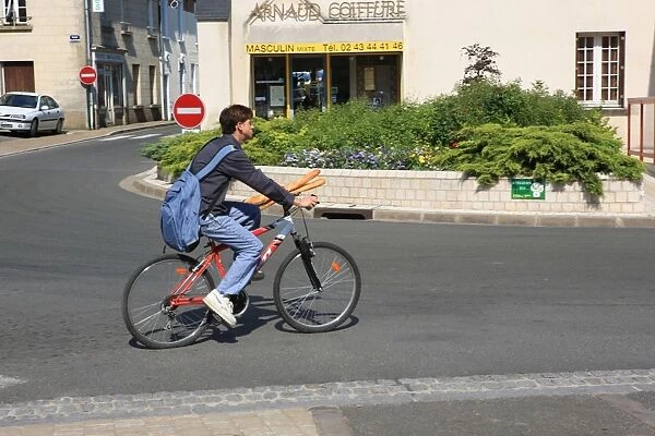 Shopping in France. A boy on a bike shopping for bread in the French town