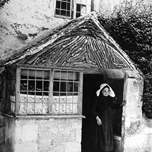 Old woman at cottage porch, 1890s