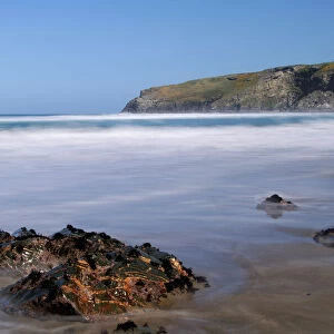 A rising tide swirls around a rock on the beach at Trebarwith Strand, Cornwall, England, United Kingdom, Europe