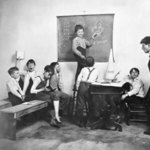 ELEMENTARY SCHOOL, 1902. Children misbehaving in an American classroom. Staged photograph