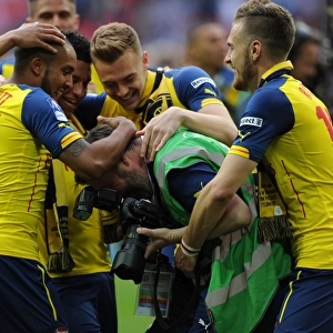 Arsenal photographer Stuart MacFarlane is grabbed by Aaron Ramsey and Theo Walcott after the match