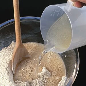 Pouring water and honey on whole wheat flour in mixing bowl